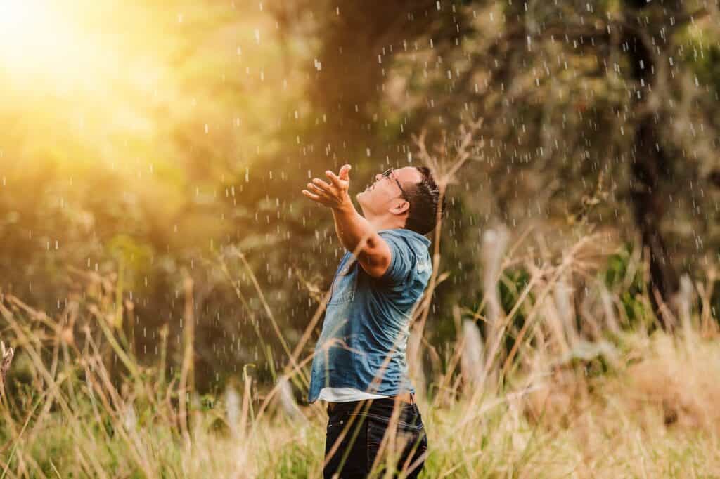 Photo of a man worshiping and praising out in a field..
